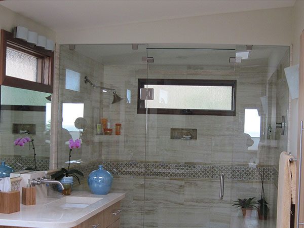 Master bathroom by Anthony's Tile: a glass shower enclosure and large-format wall tile with a mosaic accent band.