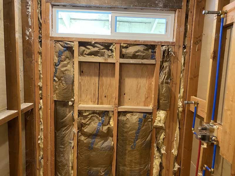 Open stud wall with insulation and plumbing roughed in.