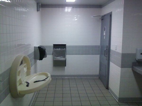Commercial restroom tiled floor to wall in white and grey.