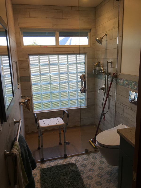 Bathroom with a glass-block window, curbless shower and patterned floor tile.