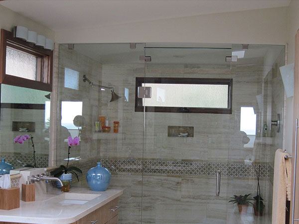 Master bathroom with a glass shower enclosure and a mosaic accent band running through large-format wall tile.