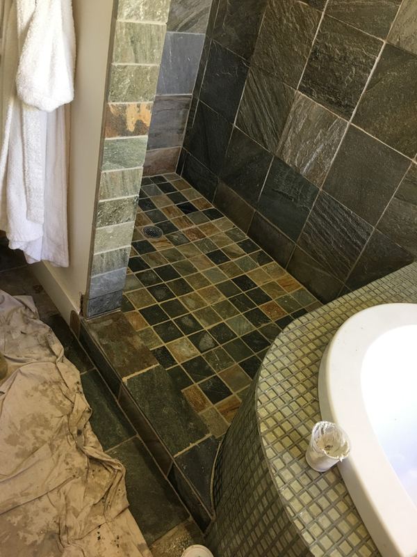 Green and slate tile tub surround with a decorative border.