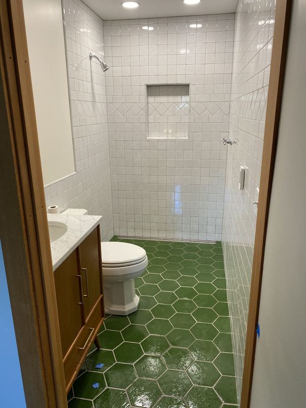 White subway-tile shower with a recessed niche above a green hexagon tile floor.